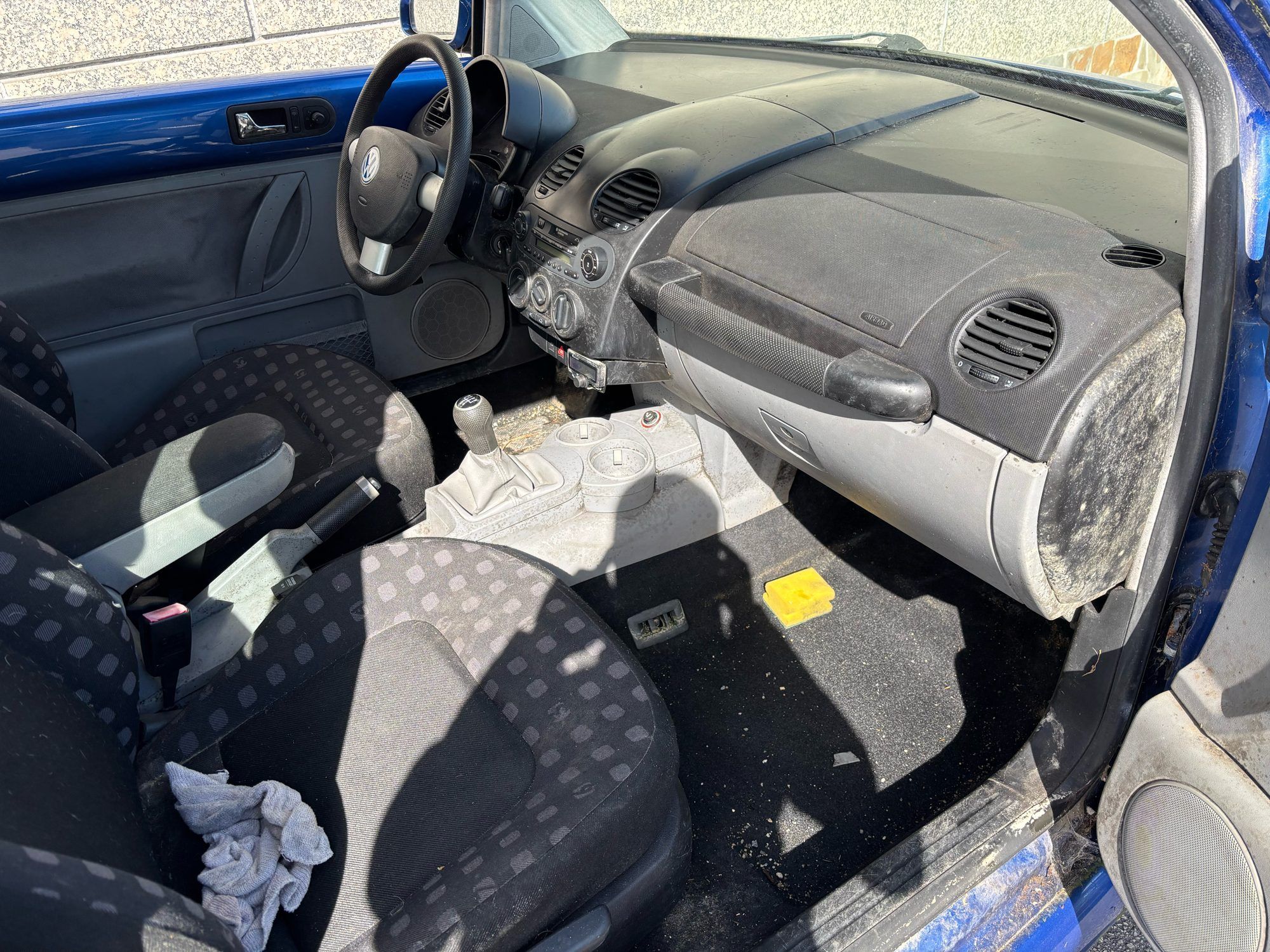 Interior de un Volkswagen Beetle con asientos y suelo sucios antes de la limpieza
