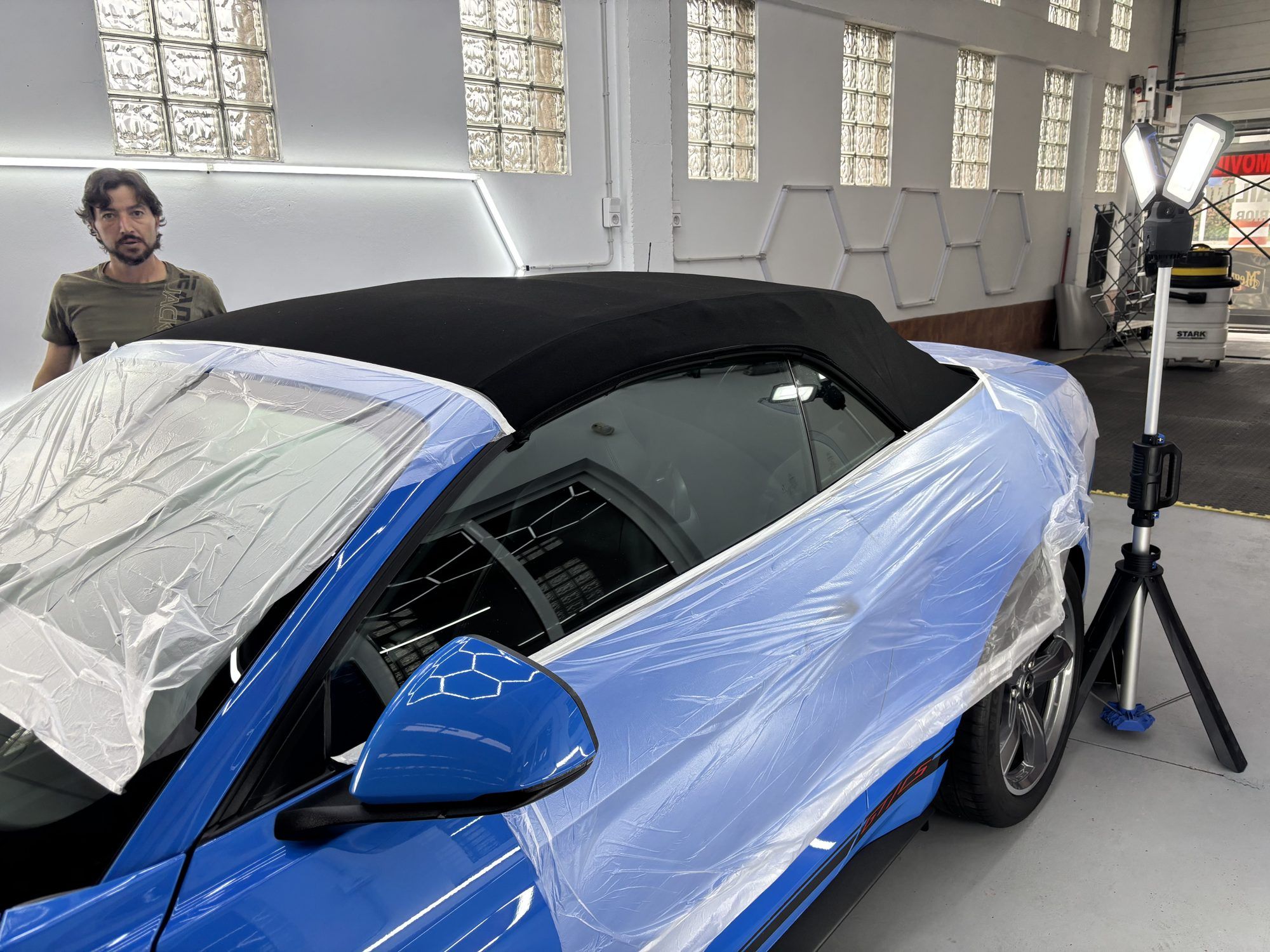 Ford Mustang descapotable con la carrocería protegida para trabajar la capota de tela