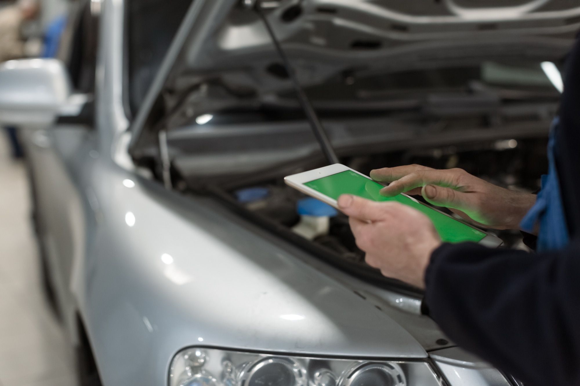 Mecánico revisando el motor de un vehículo con una tableta